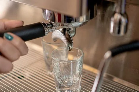 Hand holding coffee machine filter holder with two small cups down. Stock Photos