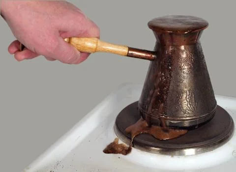 Hand holding coffee maker with boiling coffee on electric burner. Foto stock