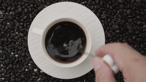 Hand holding coffee stirring spoon in white cup on table. Top view Stock Footage 242829206