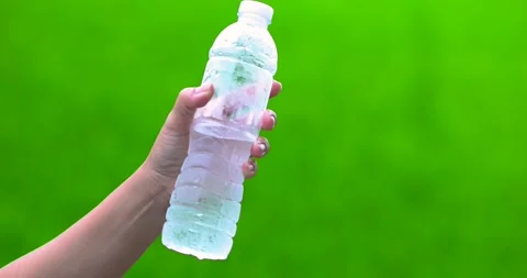 Hand holding a cold bottled water with condensation, green background, hydr.. Stock Footage 340213041