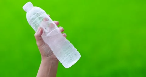Hand holding a cold bottled water with condensation, green background, hydr.. Stock Footage 340607016