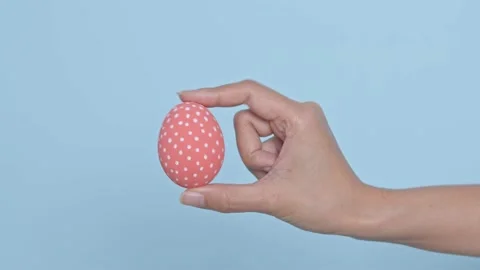 Hand holding colorful Easter egg on blue background. Easter holiday decoratio Stock Footage 149813401