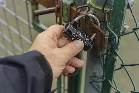 Hand Holding Combination Padlock Securing Chain-Link Fence Gate Stock Photos