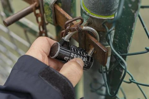 Hand Holding Combination Padlock Securing Chain-Link Fence Gate Stock Photos