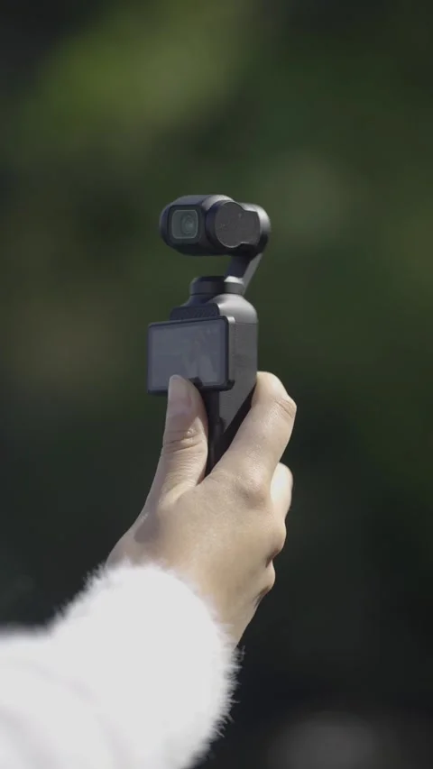 Hand Holding a Compact Gimbal Camera Outdoors Stock Footage 308576795
