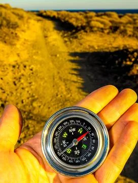 A hand holding a compass pointing to the north Foto stock