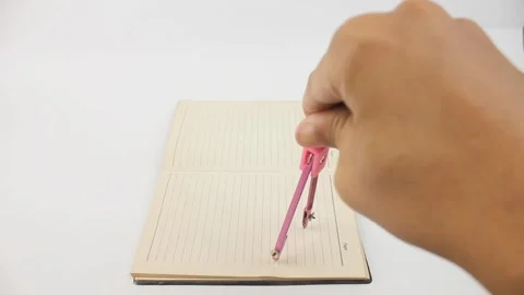 Hand holding compass school drawing on book Stock Footage 325474608