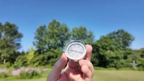 Hand Holding Compass in Sunny Green Park Stock Footage 339987755