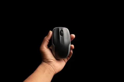 Hand holding computer mouse isolated on the black background. above view of c Stock Photos