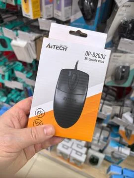 Hand holding a computer mouse package in a vibrant electronics store aisle 스톡 사진