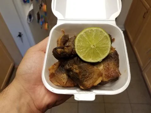 Hand holding container of fried pork with lime Stock Photos