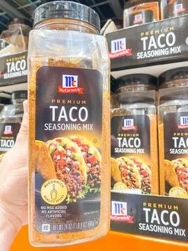 A hand holding a container of McCormick Premium Taco Seasoning Mix in a store Fotos de archivo