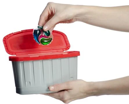 Hand holding container washing laundry capsules Stock Photos