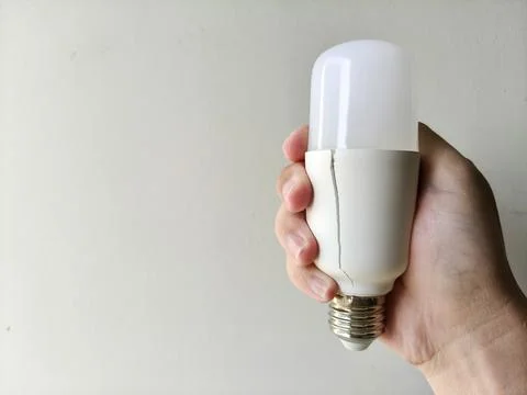 Hand holding of cracked plastic socket on the light bulb is caused by heat 스톡 사진