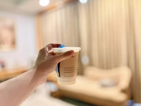 Hand holding a cup of bubble tea with a blue straw. Stock Photos