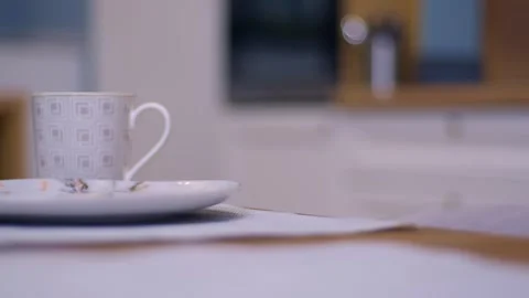 Hand holding cup of coffee hovers above plate on wooden table Видео 267642004