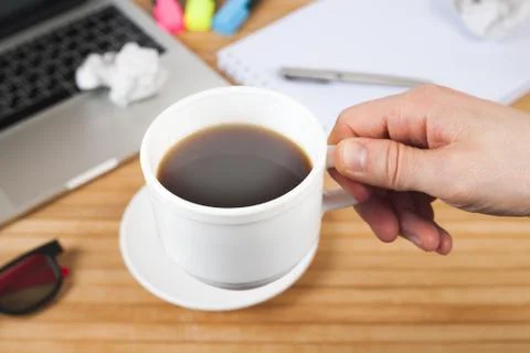 Hand holding cup coffee on work table background Stock Photos