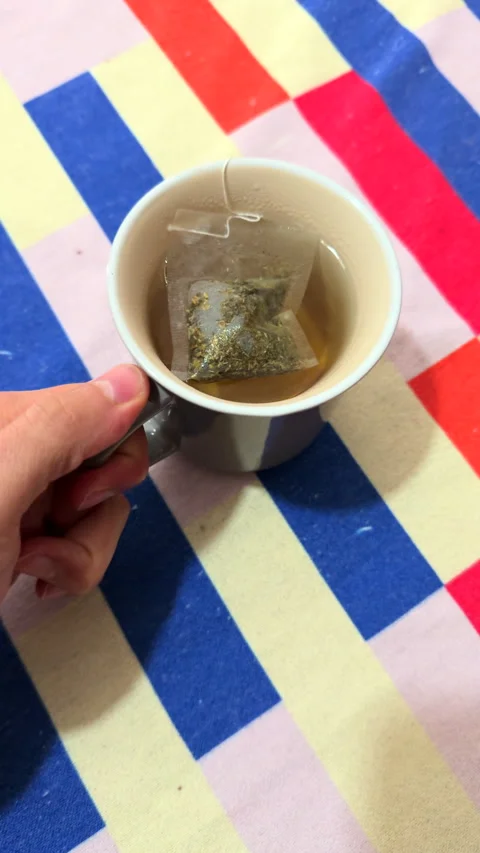 Hand holding a cup with tea bag Видео 309596465