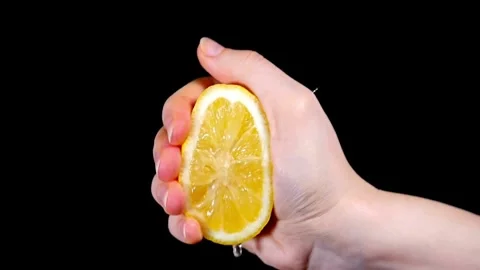 Hand holding a cut slice of lemon and squeeze the fresh juice with black Stock-Footage 336588736