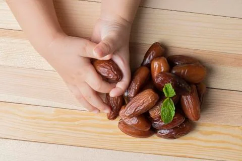 Hand holding dates on rustic background, flat lay Stock Photos