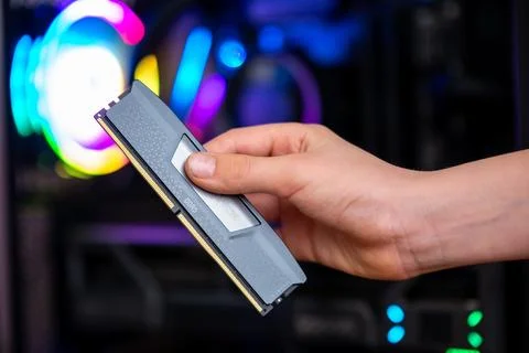 Hand holding ddr5 memory module inside gaming pc with rgb lighting, represe.. Stock Photos