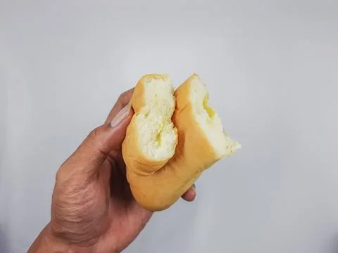 Hand holding a delicious split sweet bun with yellow creamy filling Stock Photos