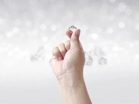 Hand holding diamond ring on shining bokeh background Foto stock