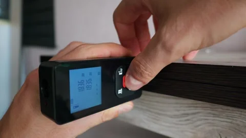 Hand Holding Digital Laser Distance Meter Measuring Wooden Shelf Surface Stock Footage 339361867
