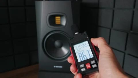 Hand Holding Digital Sound Level Meter in Front of Professional Studio Speaker Stock Footage 338100206