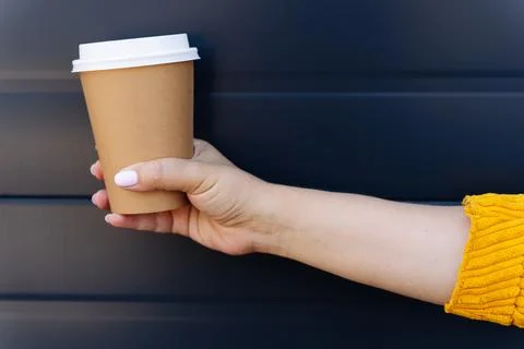 Hand holding disposable coffee cup on blue background Stock Photos