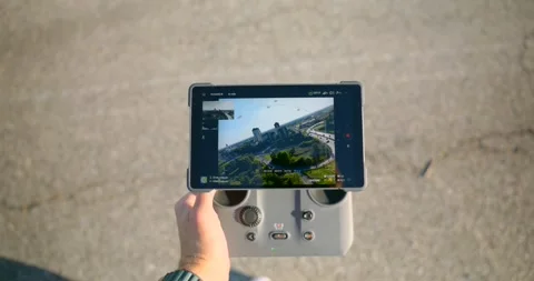 Hand holding DJI remote controller with smartphone screen outdoors. Close up Stock Footage 336775308