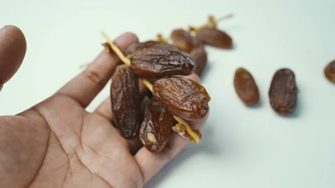 Hand Holding Dried Fresh Dates, A hand holding a bunch of dried dates on a .. Stock Footage 304974562