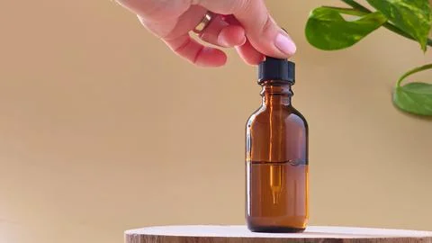 Hand holding dropper on amber glass bottle on wood slice. Stock Photos