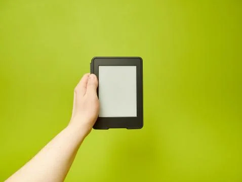 Hand holding an e-book reader on a green wall Stock Photos