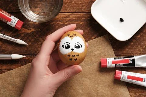 Hand holding Easter egg with cute owl face, hand-painted with acrylic paints, Stock Photos