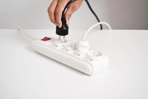Hand holding electric plug, Multiple socket with connected plugs Stock Photos