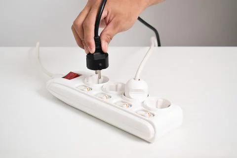 Hand holding electric plug, Multiple socket with connected plugs Stock Photos