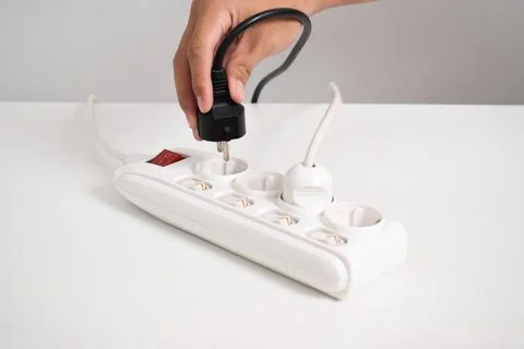 Hand holding electric plug, Multiple socket with connected plugs Stock Photos