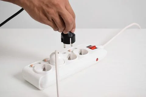 Hand holding electric plug, Multiple socket with connected plugs Stock Photos