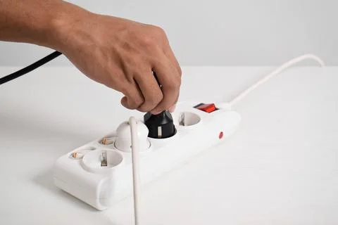 Hand holding electric plug, Multiple socket with connected plugs Stock Photos