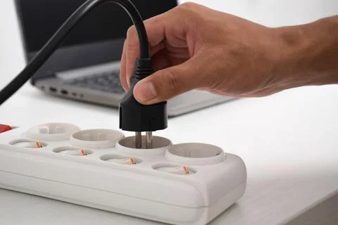 Hand holding electric plug, Multiple socket with connected plugs 写真素材