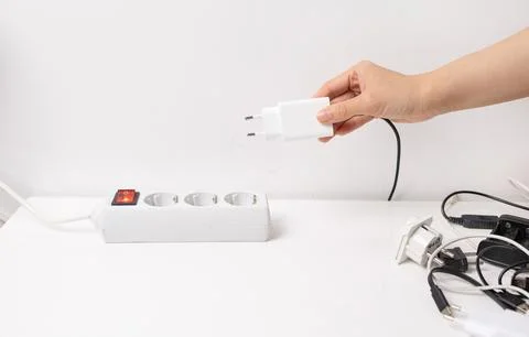 Hand holding electric plug, Multiple socket with connected plugs Stock Photos