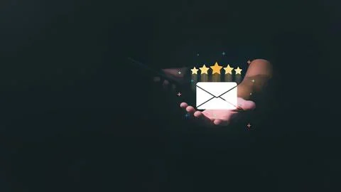 Hand holding email icon with five star rating and sparkle Stock Photos