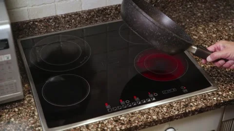 Hand holding empty black frying pan on induction stove in modern kitchen Stock Footage 323901793