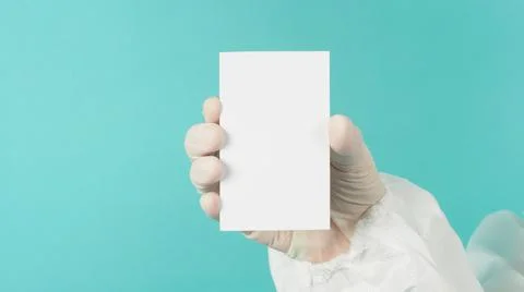 Hand holding empty blank white card.Hand with ppe suit, latex glove on green  Stock Photos