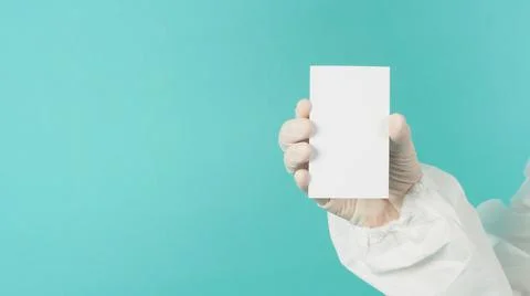 Hand holding empty blank white card.Hand with ppe suit, latex glove on green  Stock Photos