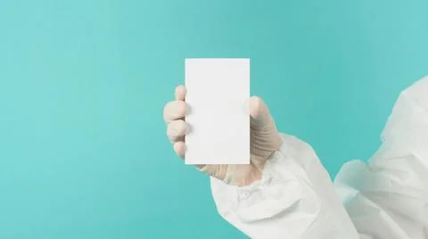 Hand holding empty blank white card.Hand with ppe suit, latex glove on green  Stock Photos