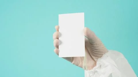 Hand holding empty blank white card.Hand with ppe suit, latex glove on green  Stock Photos