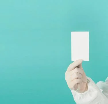 Hand holding empty blank white card.Hand with ppe suit, latex glove on green  Stock Photos