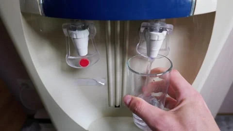 Hand Holding Empty Clear Glass Under Cold Blue Tap of Water Dispenser Stock Footage 339206296